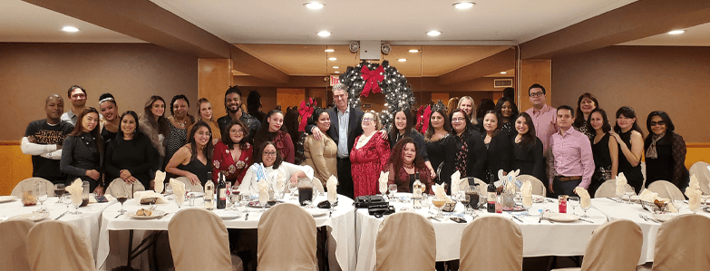 Team having dinner at Christmas in front of a giant tree at a long table